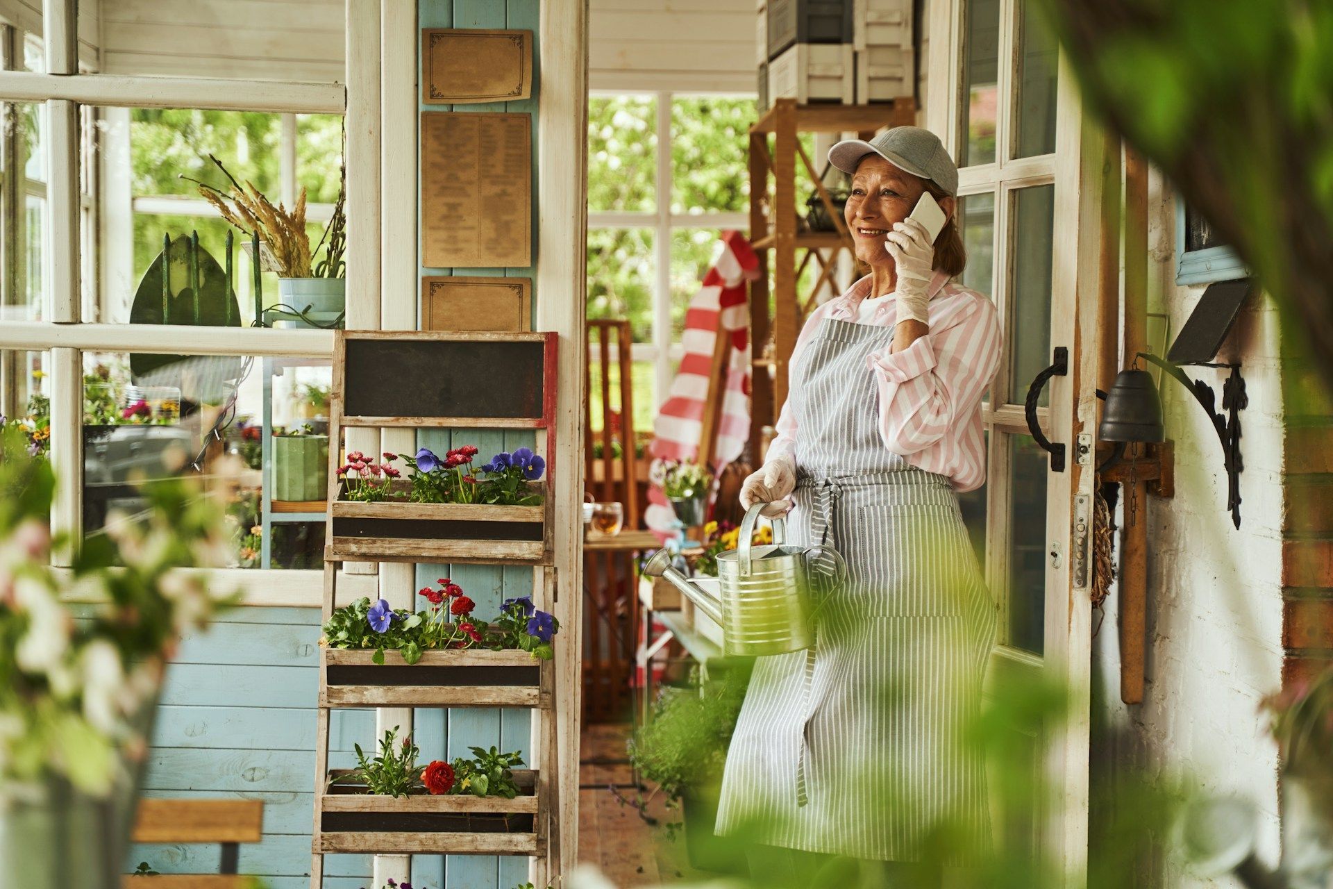 A woman is standing on a porch talking on a cell phone.