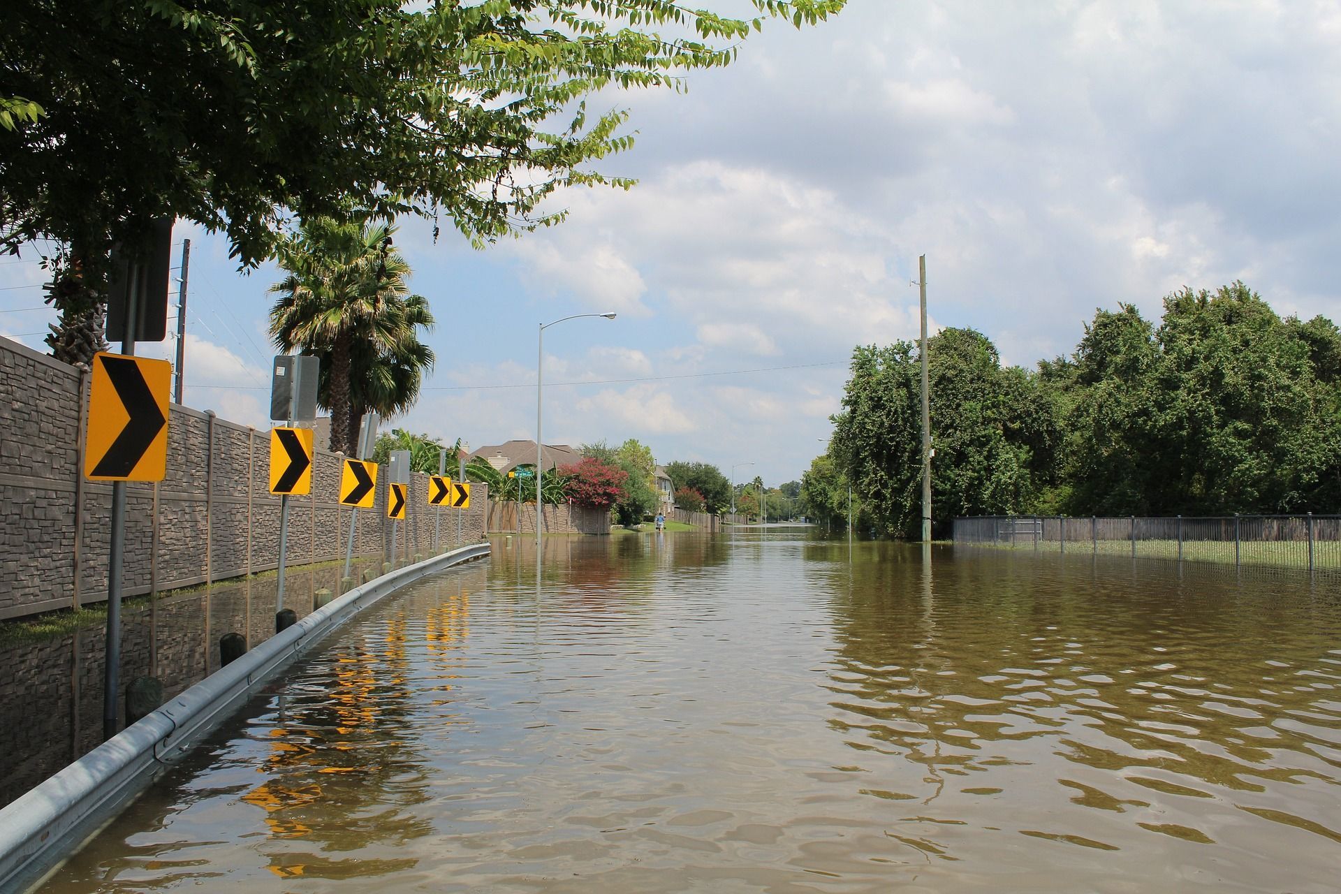 A flooded road with a yellow arrow sign in the foreground