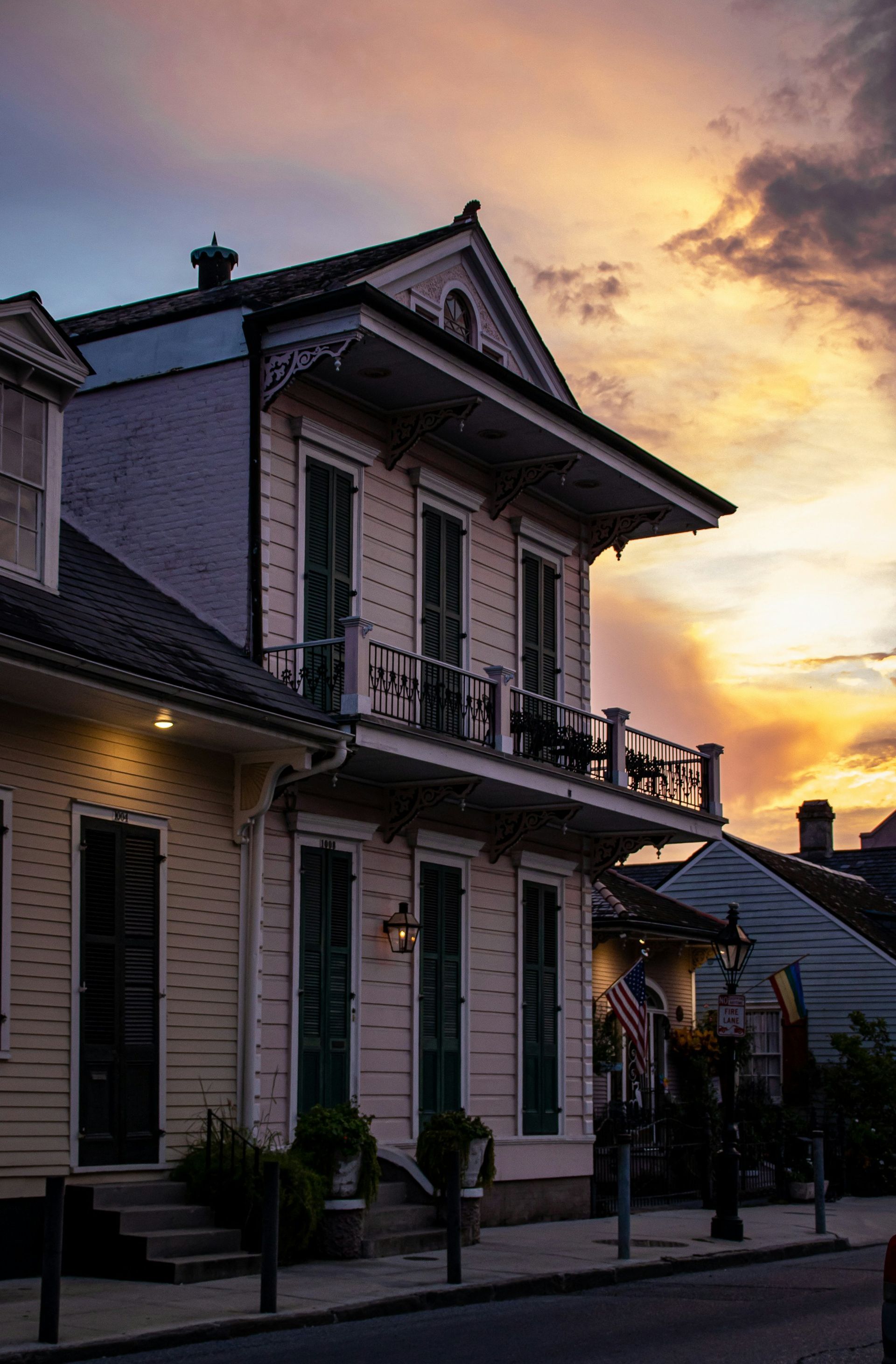 A large white house with a balcony and a sunset in the background