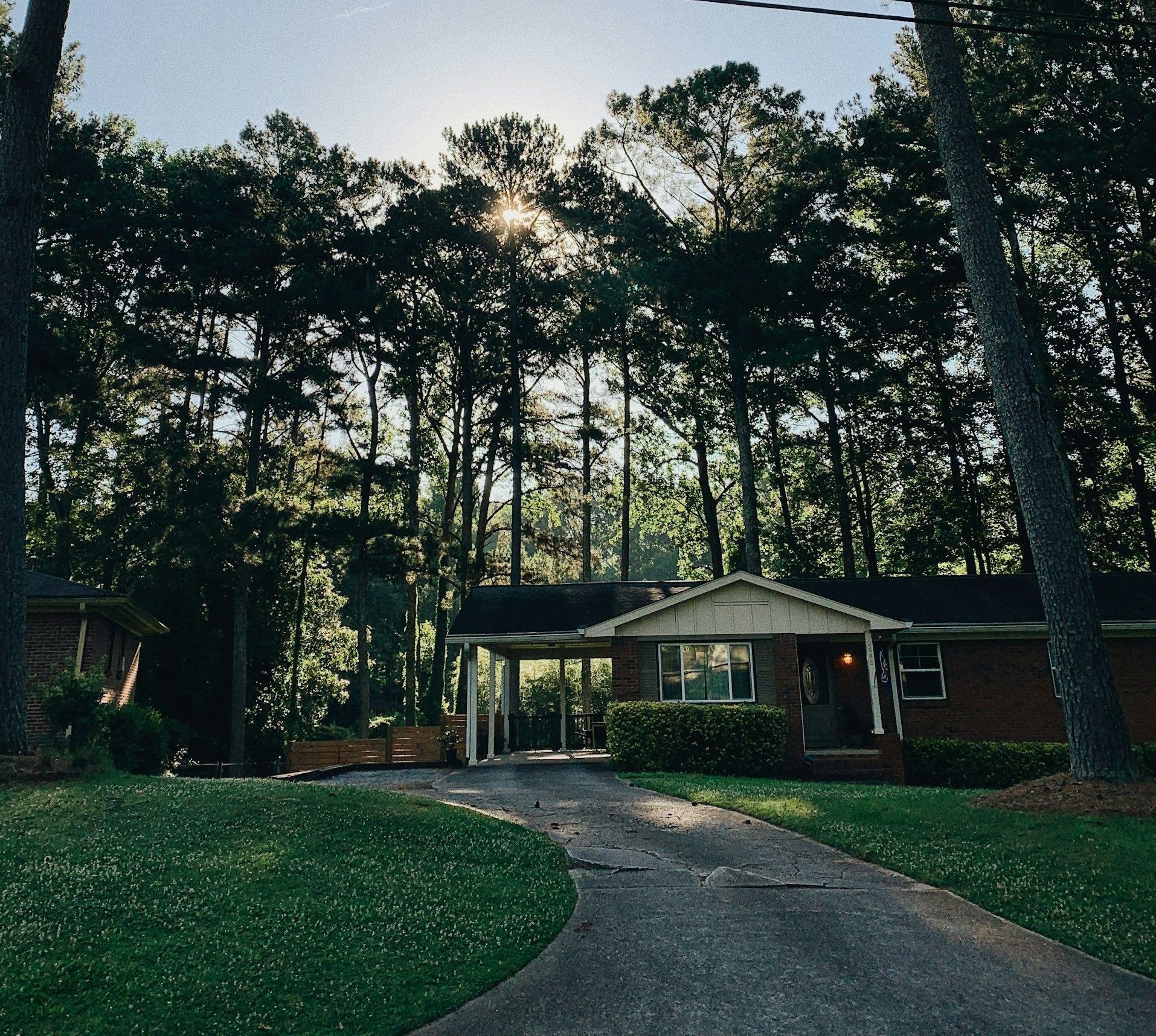 A driveway leading to a brick house surrounded by trees