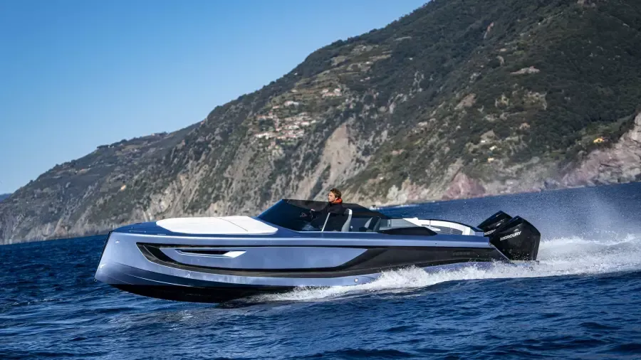 A boat is floating on top of a body of water next to a mountain.