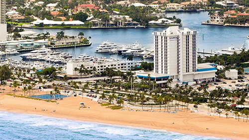An aerial view of a beach and a marina with boats in the water.