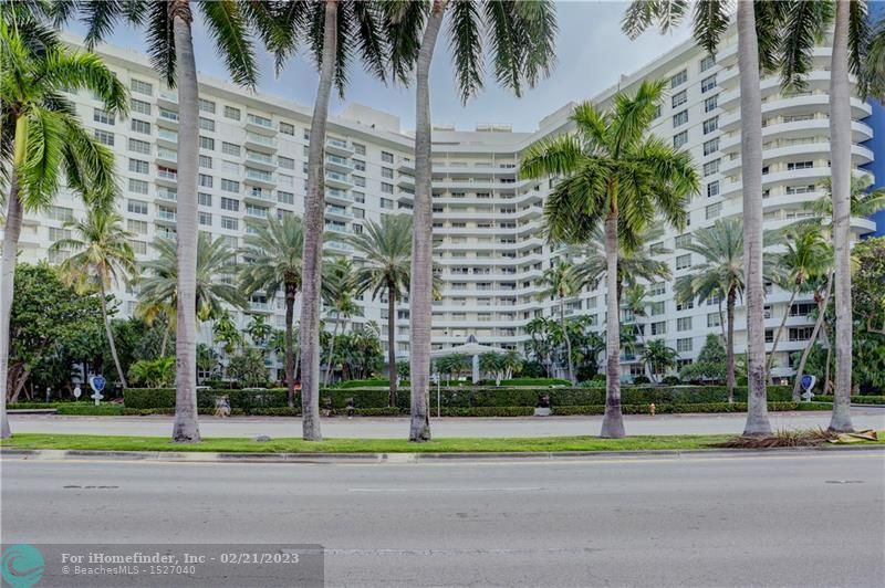 A large white building with palm trees in front of it.