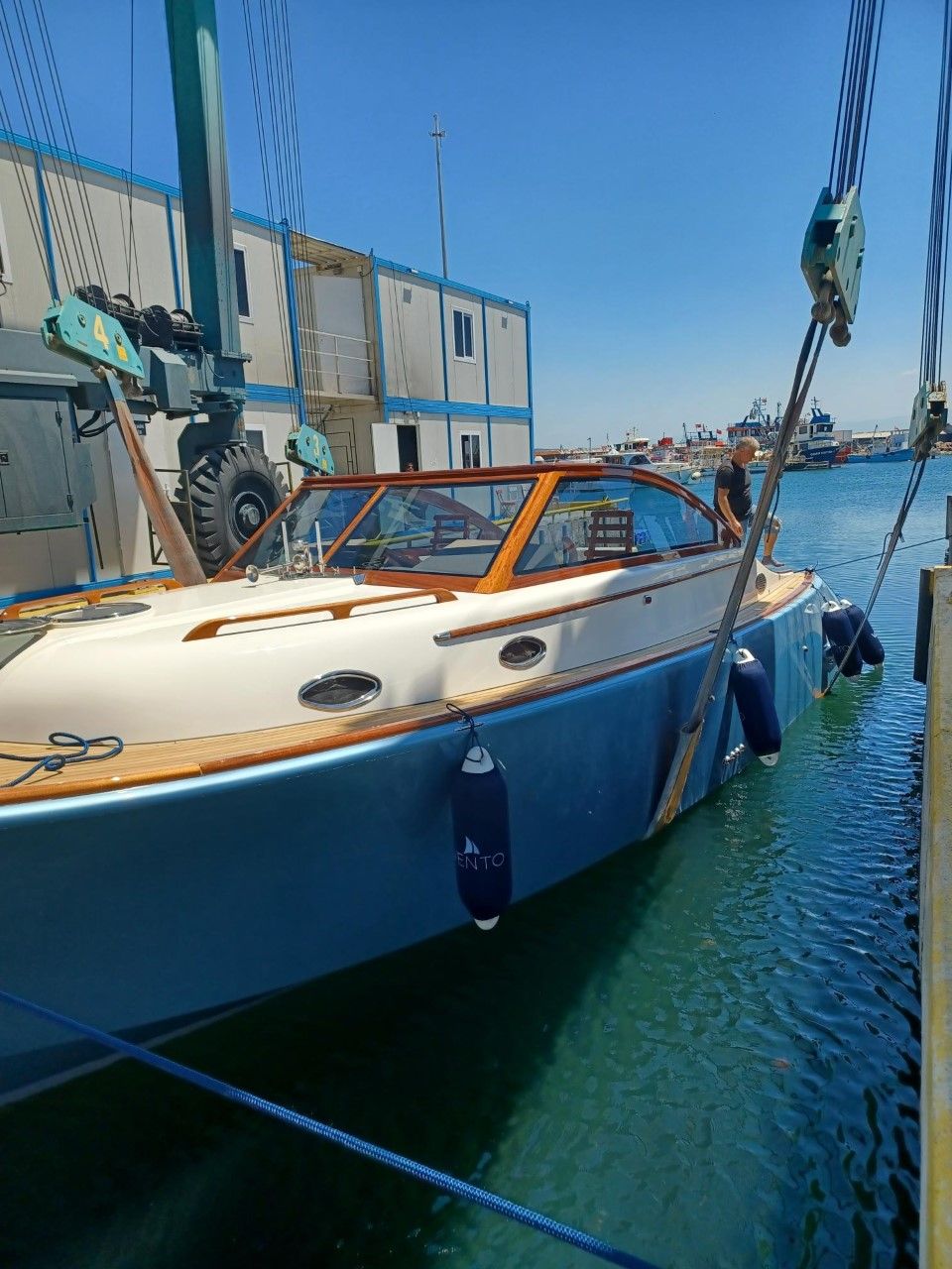 A blue and white boat is docked in a harbor.