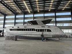 A large yacht is being built in a warehouse.
