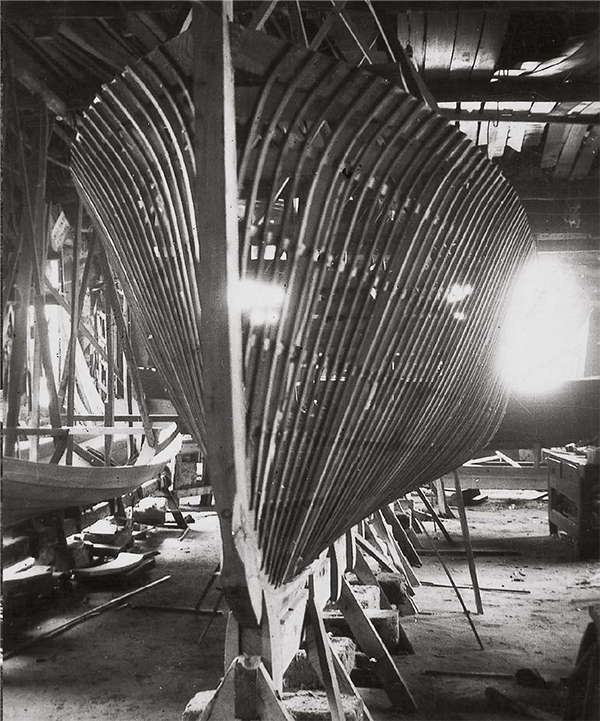 A black and white photo of a boat being built