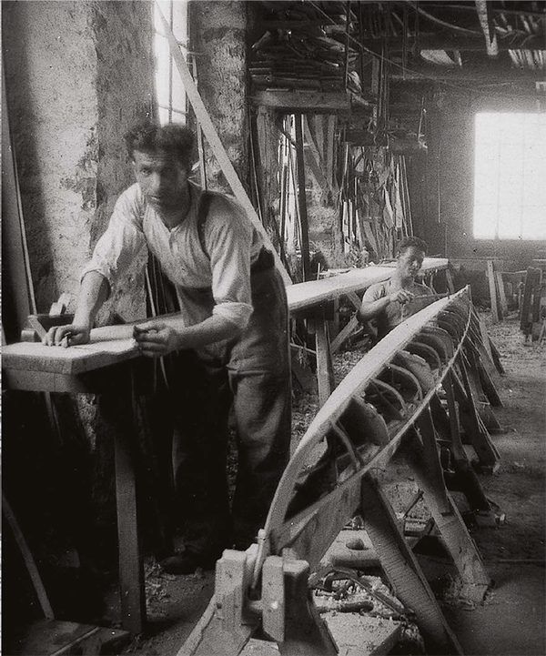 A black and white photo of a man working on a wooden boat