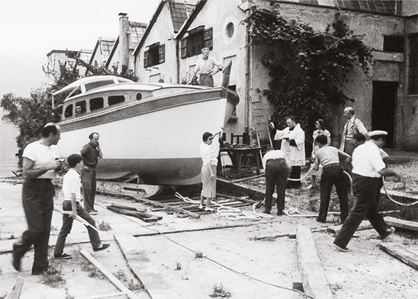 A group of people are working on a boat in front of a building