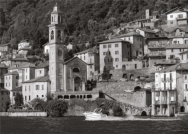 A black and white photo of a small town with a boat in the water