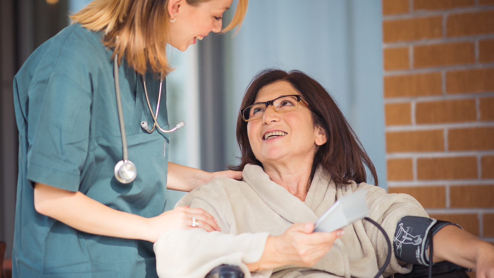 A nurse is talking to an elderly woman who is sitting on a couch.