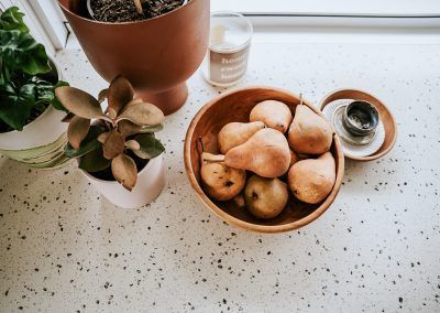 A Bowl of Potatoes is Sitting on a Counter Next to a Potted Plant — Darko's Kitchens in Kiama, NSW