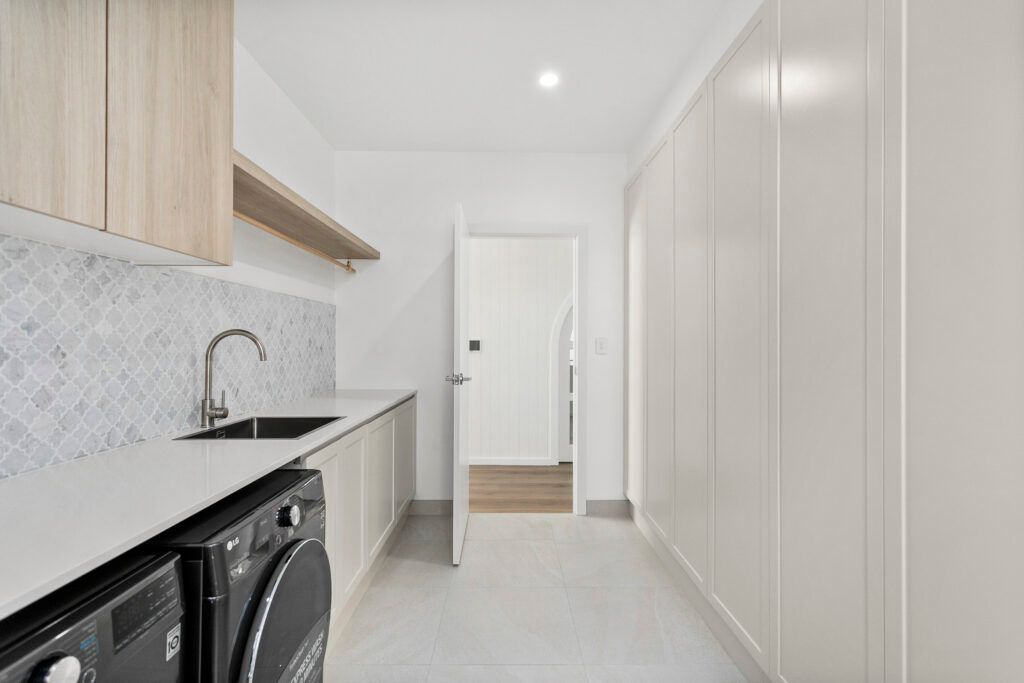 A Laundry Room With a Washer and Dryer, Sink, and Cabinets — Darko's Kitchens in Primbee, NSW