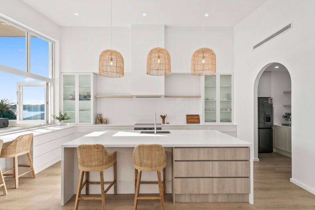 A Kitchen With a Large Island and Wicker Stools — Darko's Kitchens in Primbee, NSW