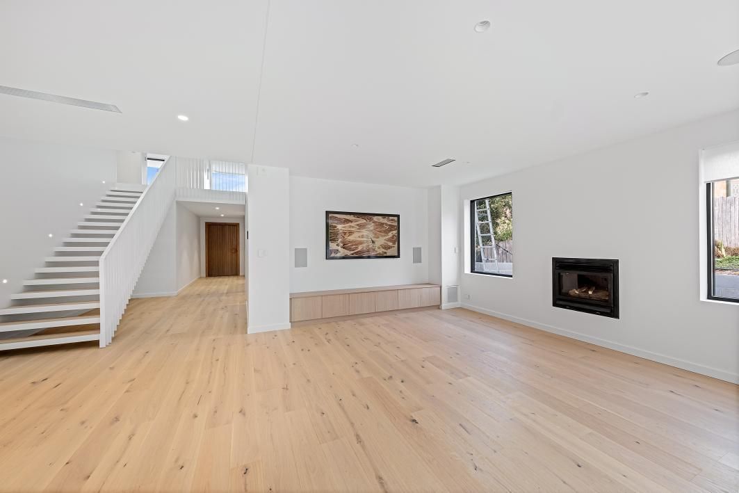 A Living Room With Hardwood Floors, Stairs , and a Fireplace — Darko's Kitchens in Woonona, NSW