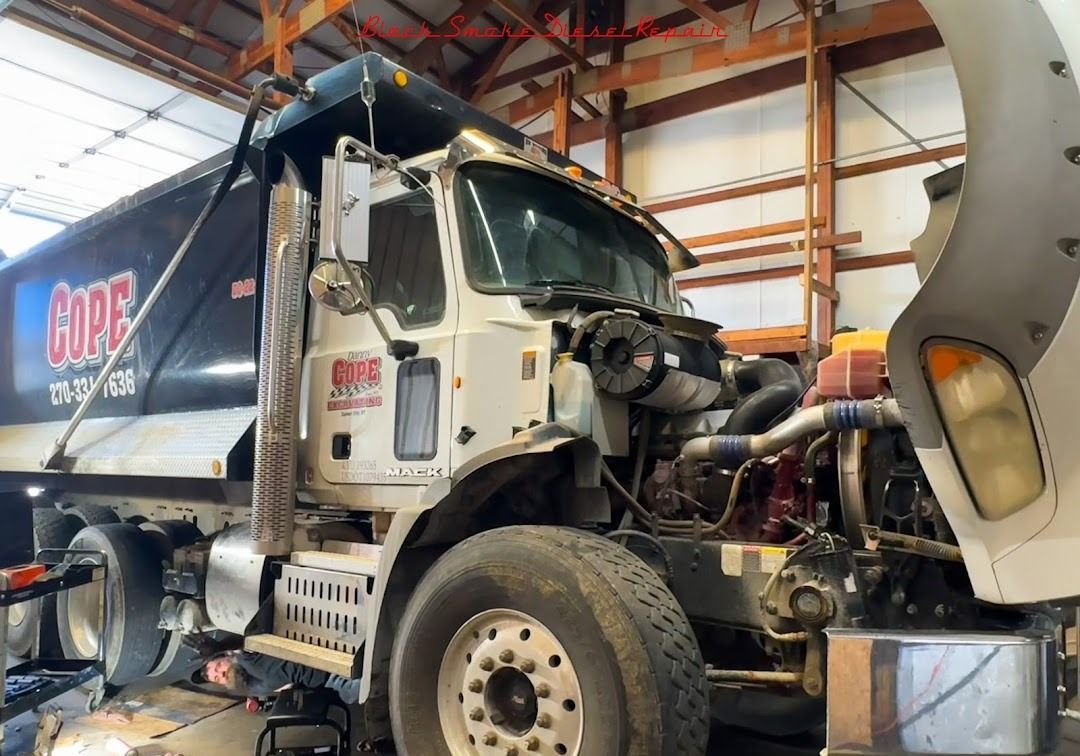 A white dump truck with a black bed labeled 