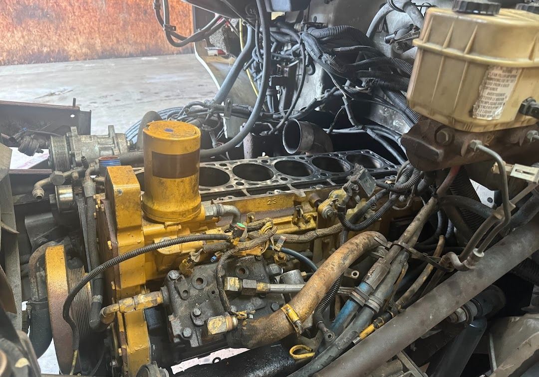 A disassembled Caterpillar diesel engine inside a truck chassis, showing exposed cylinders and yellow engine components.