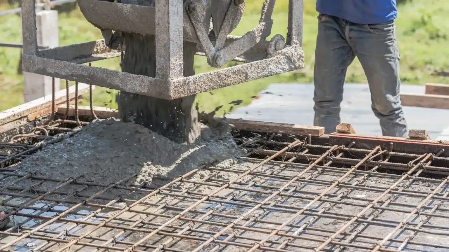 Worker pours concrete onto rebar at a construction site