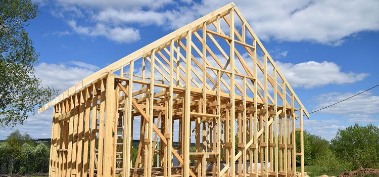 Wooden house frame under construction against a blue sky