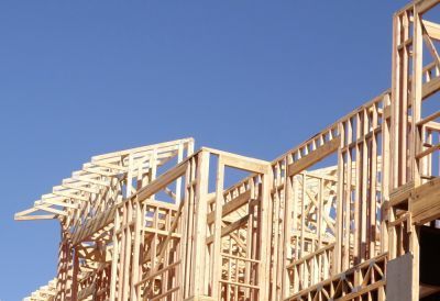 Wooden house framing under construction against a clear blue sky