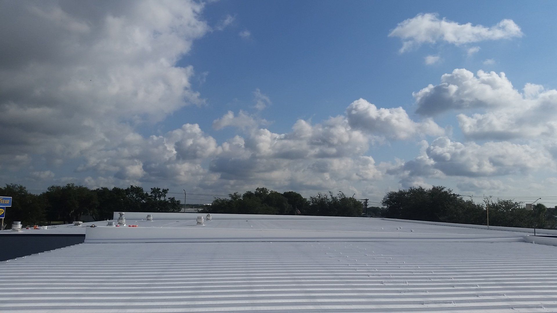 a white roof with a blue sky and clouds in the background .