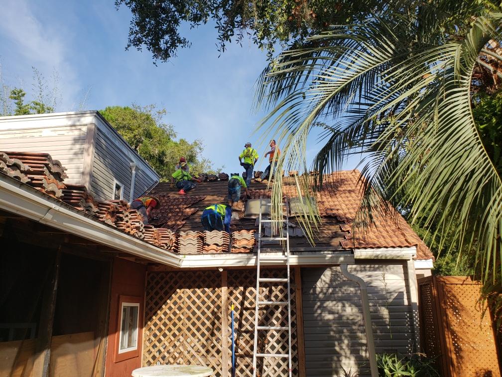 a group of men are working on the roof of a house .