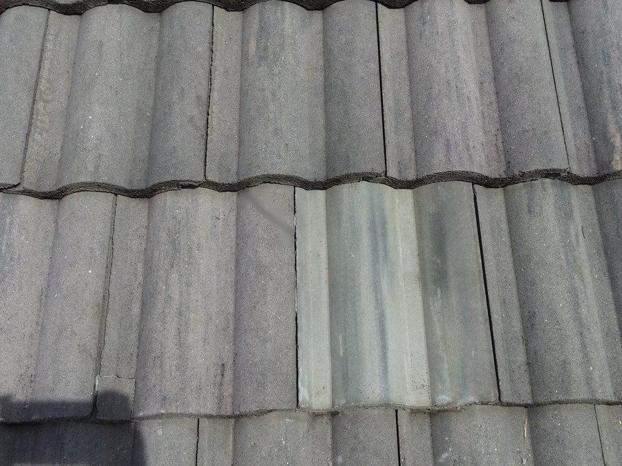 a row of gray tiles on a roof with a white tile in the middle