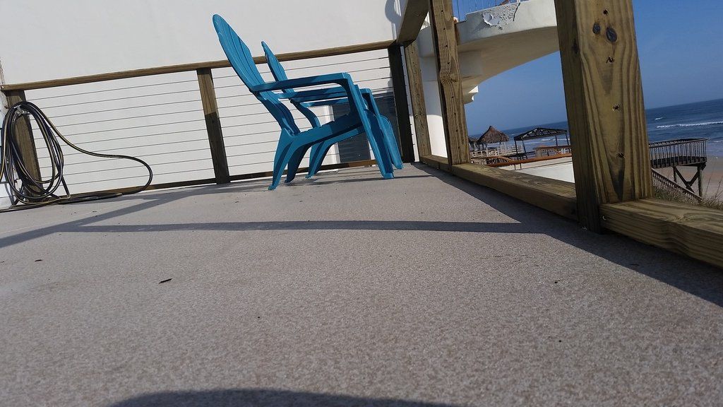 two blue chairs are sitting on a deck overlooking the ocean .