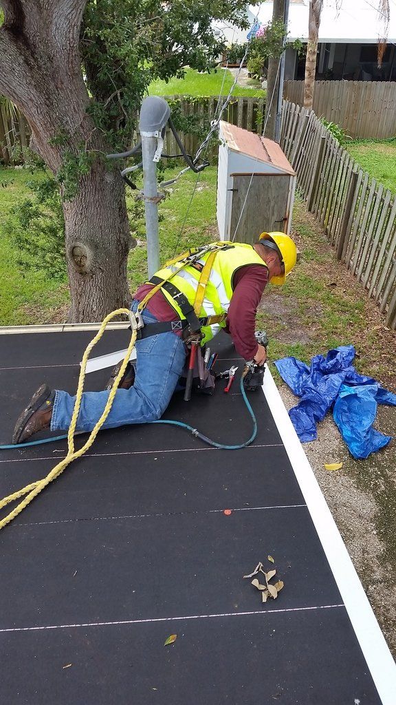 a man is kneeling on the ground working on a roof .