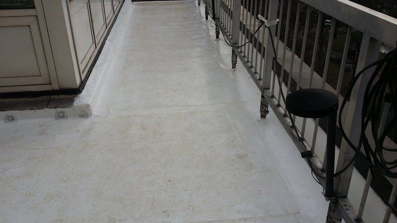a white walkway with a metal railing and a black stool .