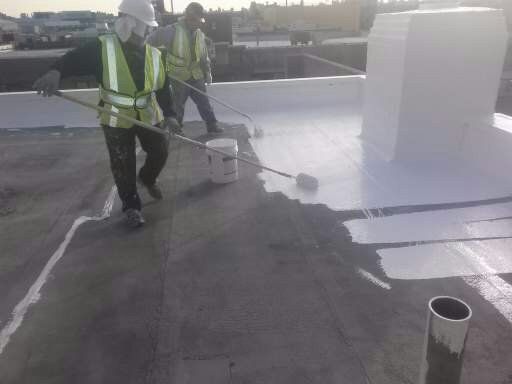 two men are painting a roof with a roller .