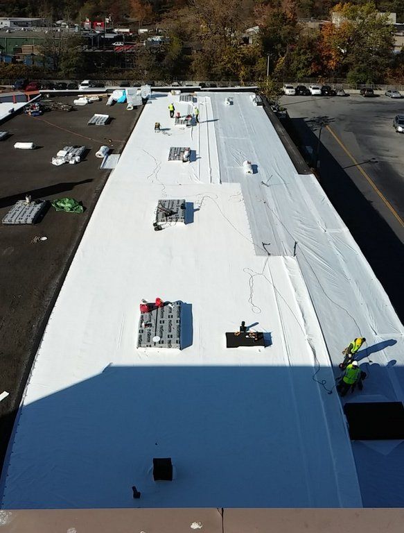 an aerial view of a white roof with workers on it