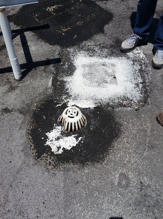 a person is standing next to a drain on the ground
