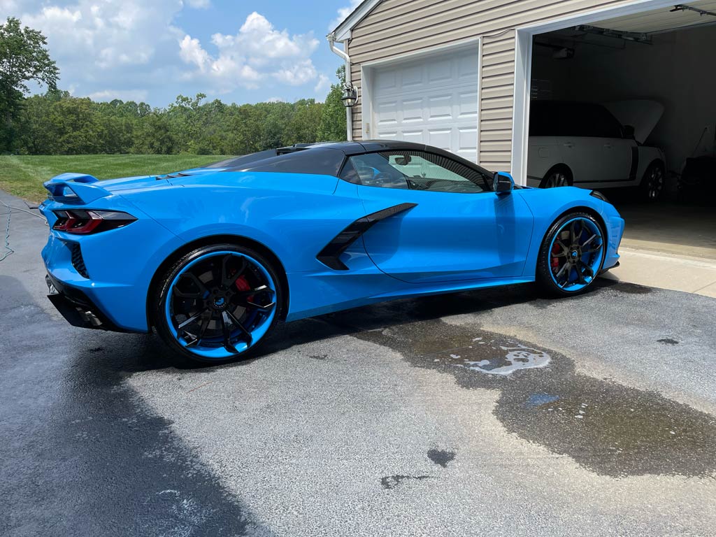 Blue sports car parked on a driveway in front of a garage.