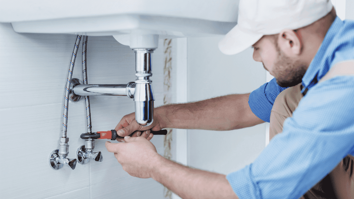 plumber working on sink pipes