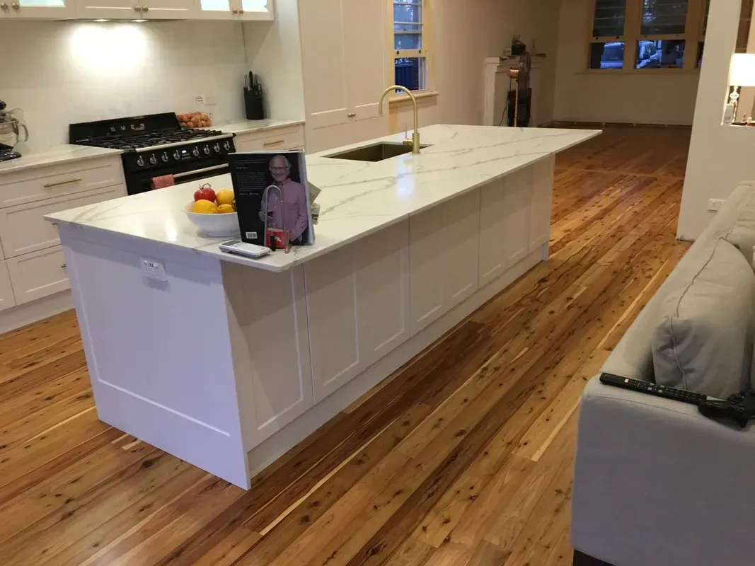 Modern kitchen with white island, hardwood floors, and a person sitting at the counter