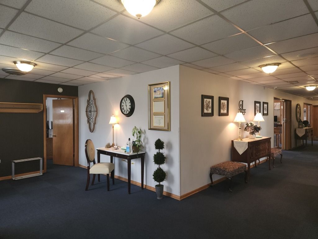 Hallway with dark blue carpet, white walls, and decorative furniture; various doors.