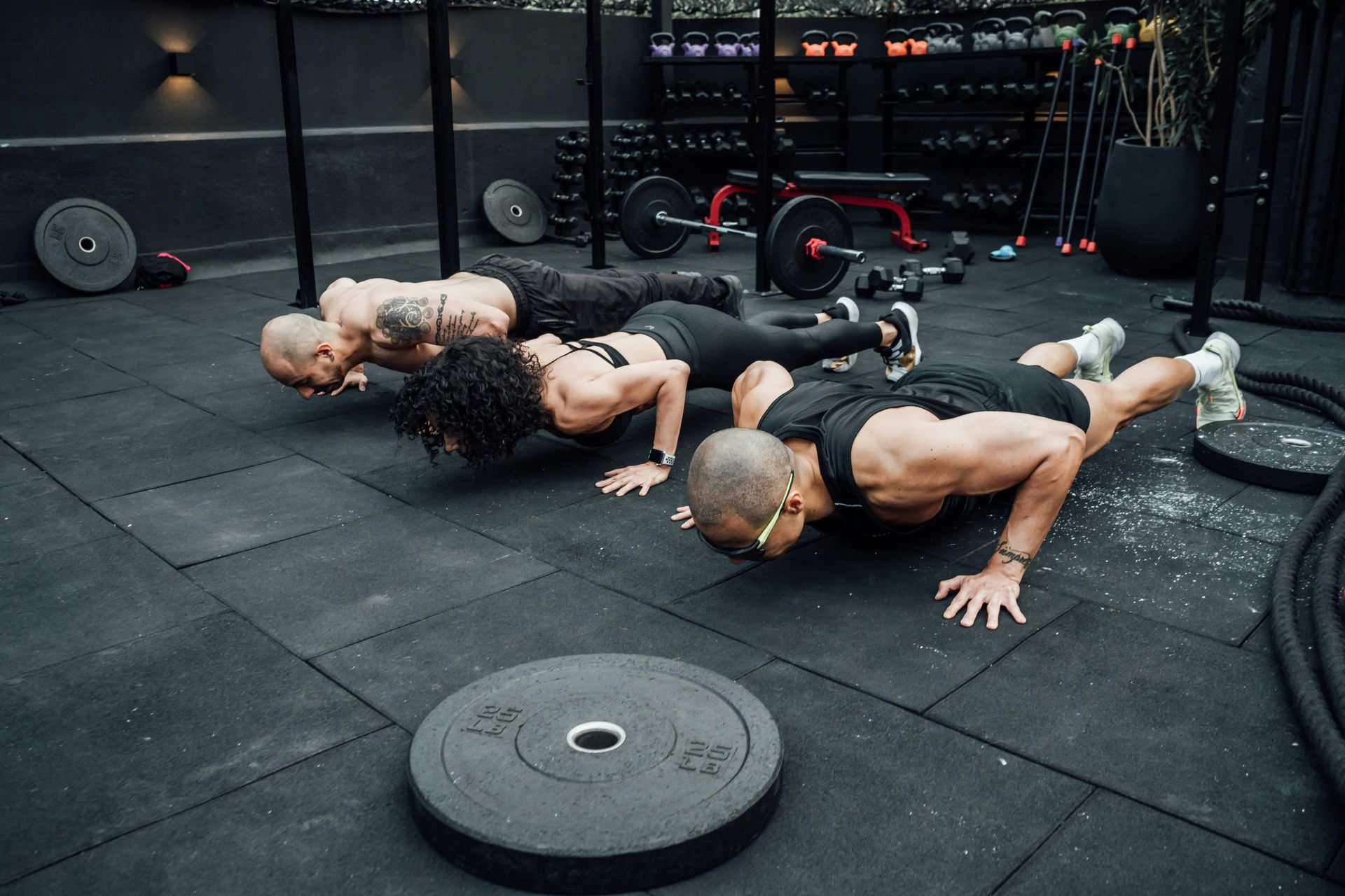 Woman hanging from pull-up bar with spotter in a gym.