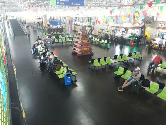 Homem na sala de controle falando ao telefone, supervisionando ônibus estacionados ao ar livre sob abrigo.