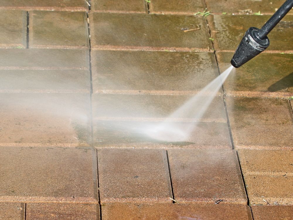 Pressure Washer Spraying Water Onto Brown Brick Pavers — Integral Cleaning Services in Aberdare, NSW