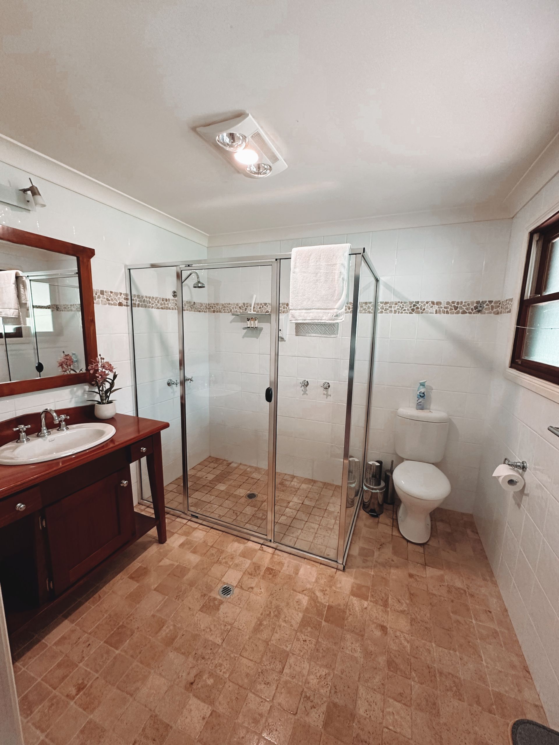 Bathroom with brown vanity, shower, toilet, and tiled floor  — Integral Cleaning Services in Aberdare, NSW