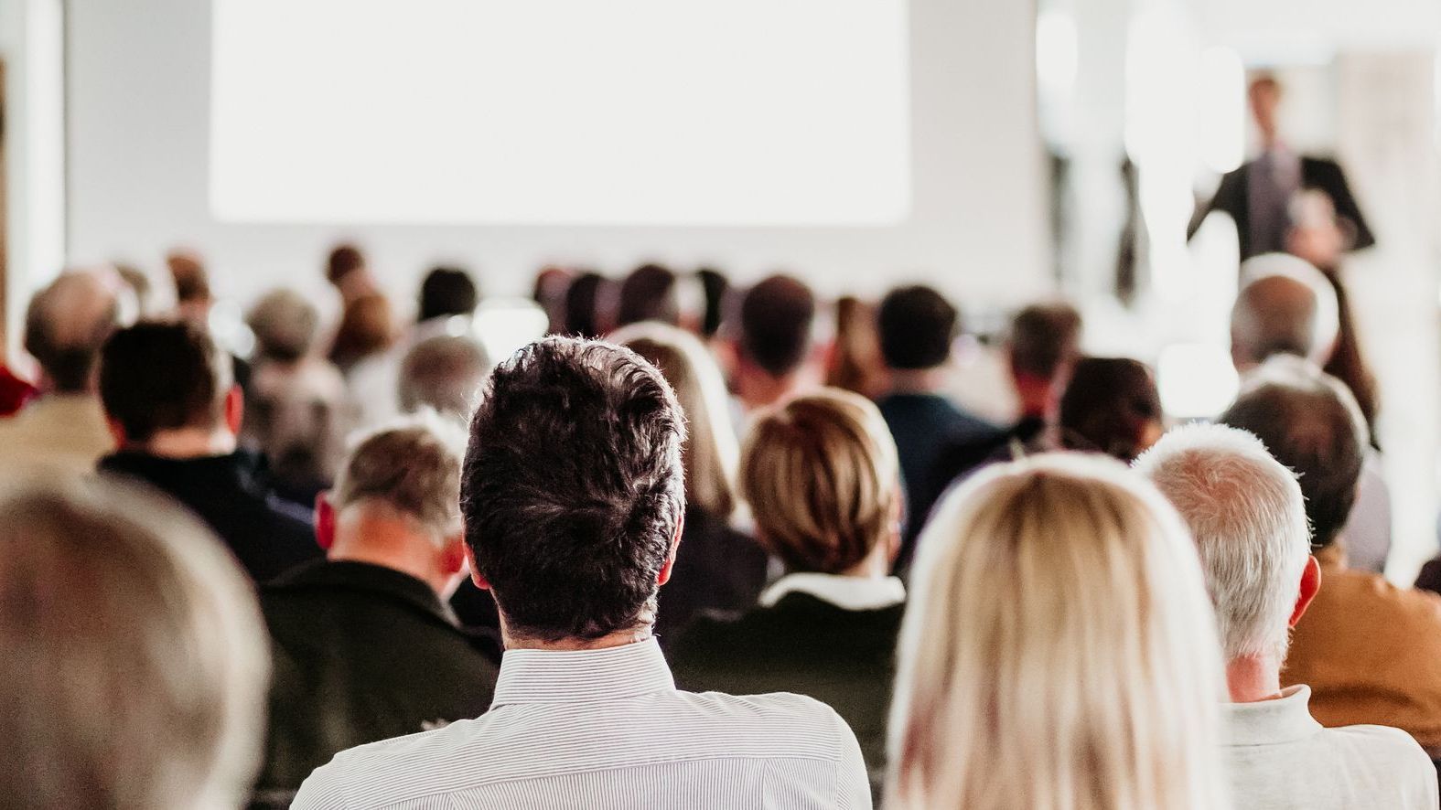 A group of people are sitting in a room watching a presentation.