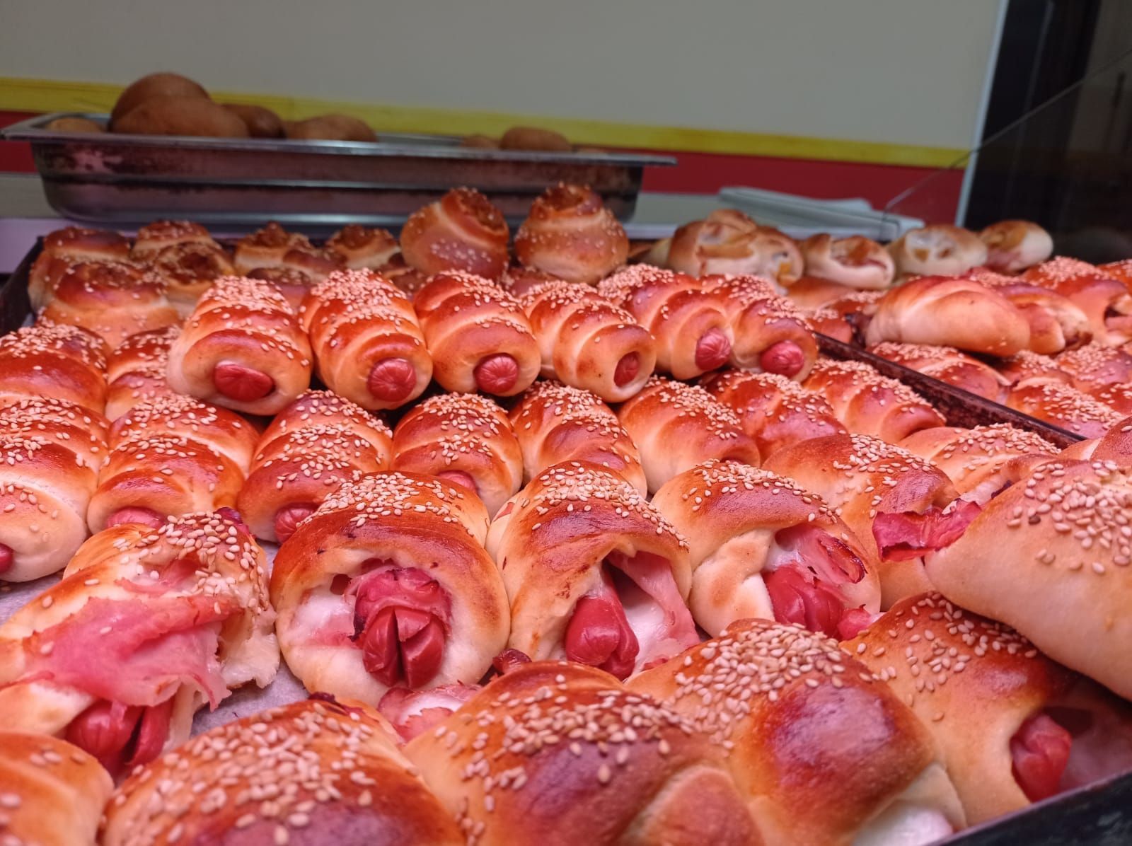 Un mucchio di panini con dentro gli hot dog sono seduti su un tavolo.