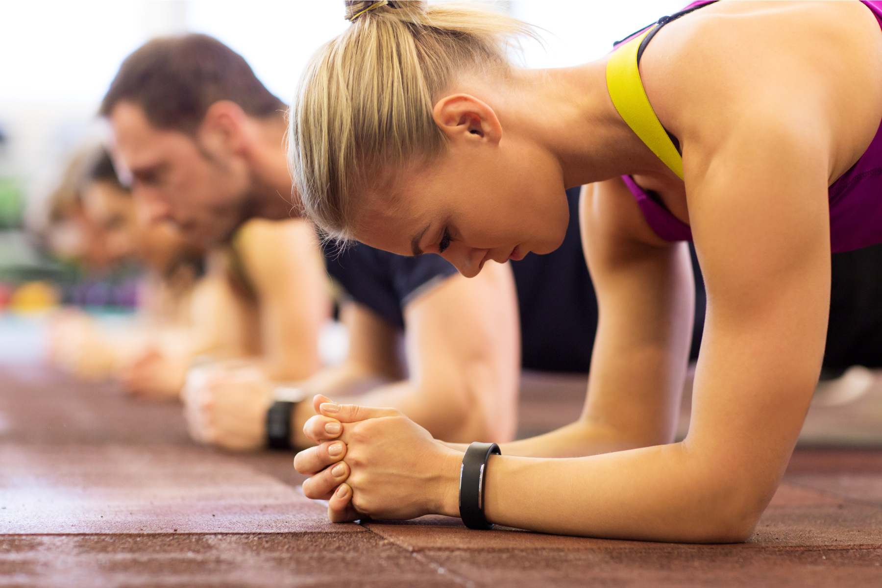 A group of people are doing plank exercises in a gym.