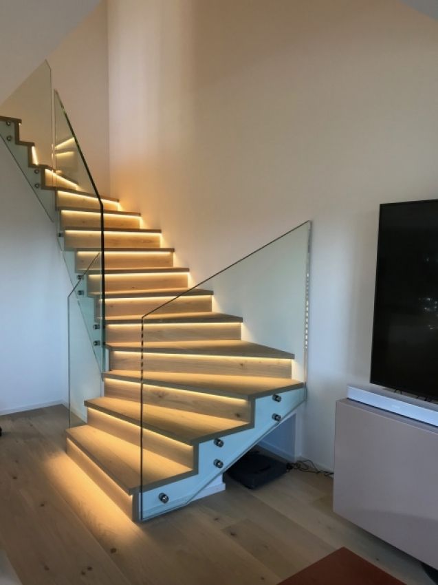 un escalier avec un garde-corps en verre et luminaires sur marches