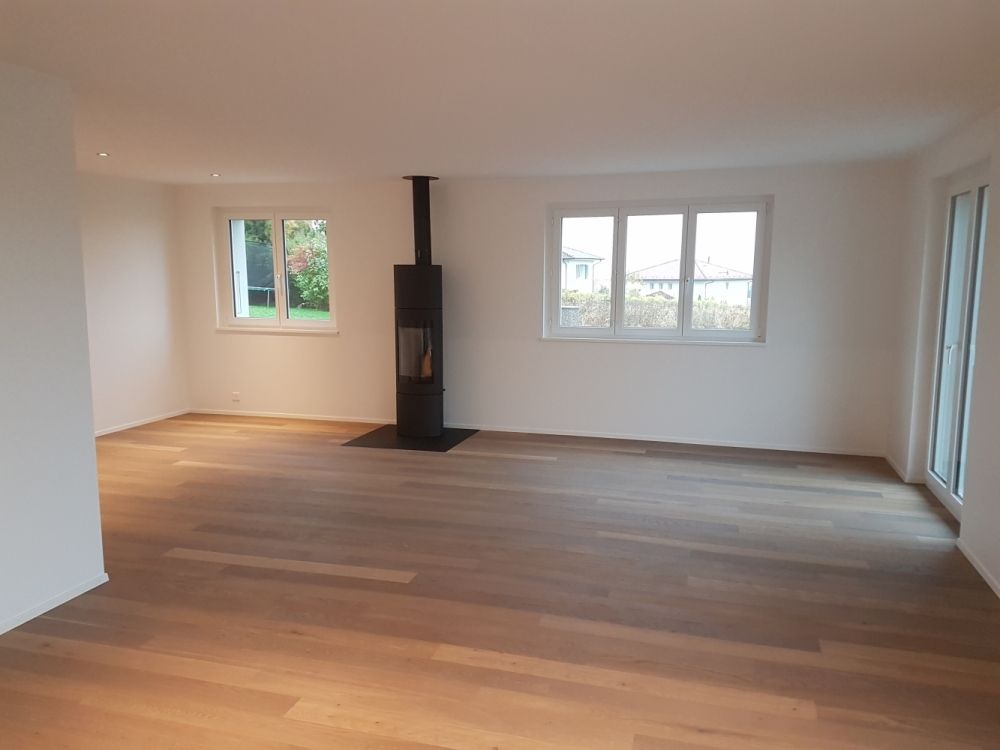 une pièce blanche avec un plancher en bois et une cheminée