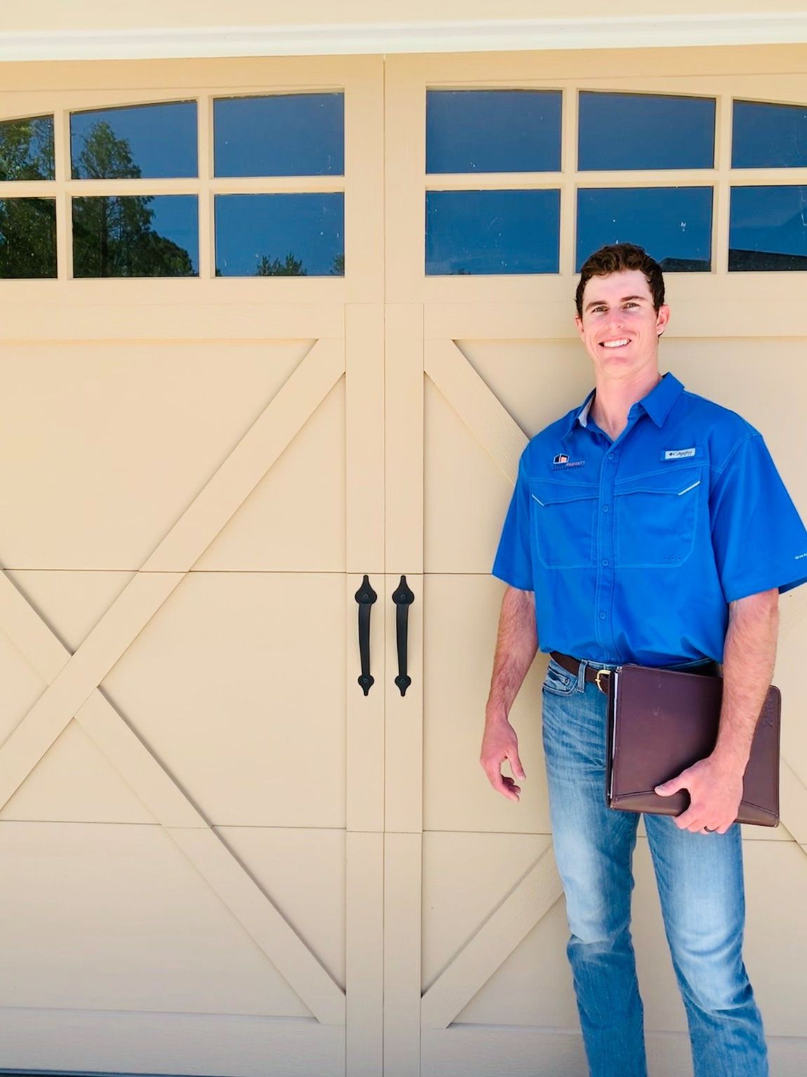 A man in a blue shirt is standing in front of a garage door