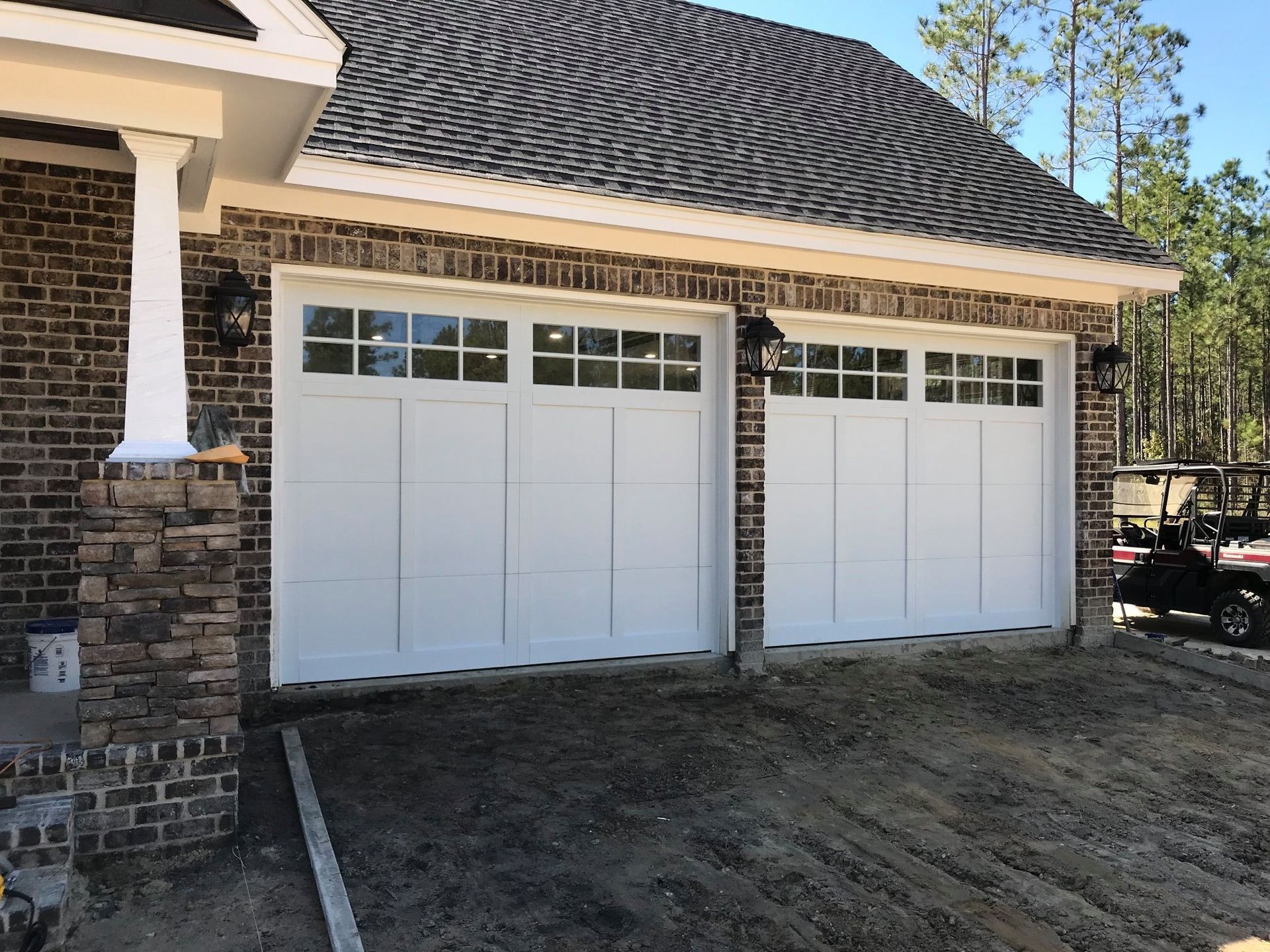 A house with two white garage doors and a golf cart parked in front of it.