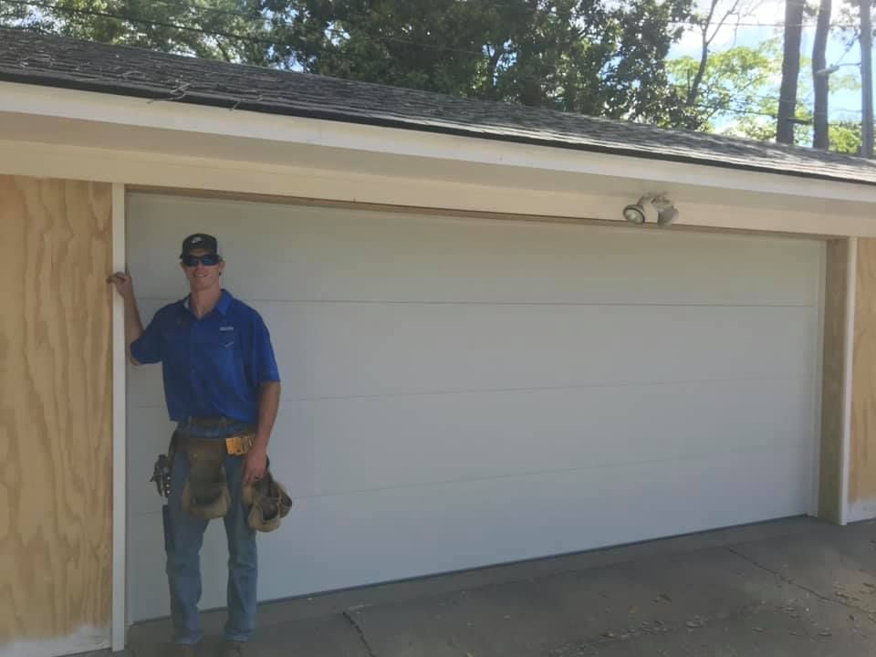 A man is standing in front of a white garage door.
