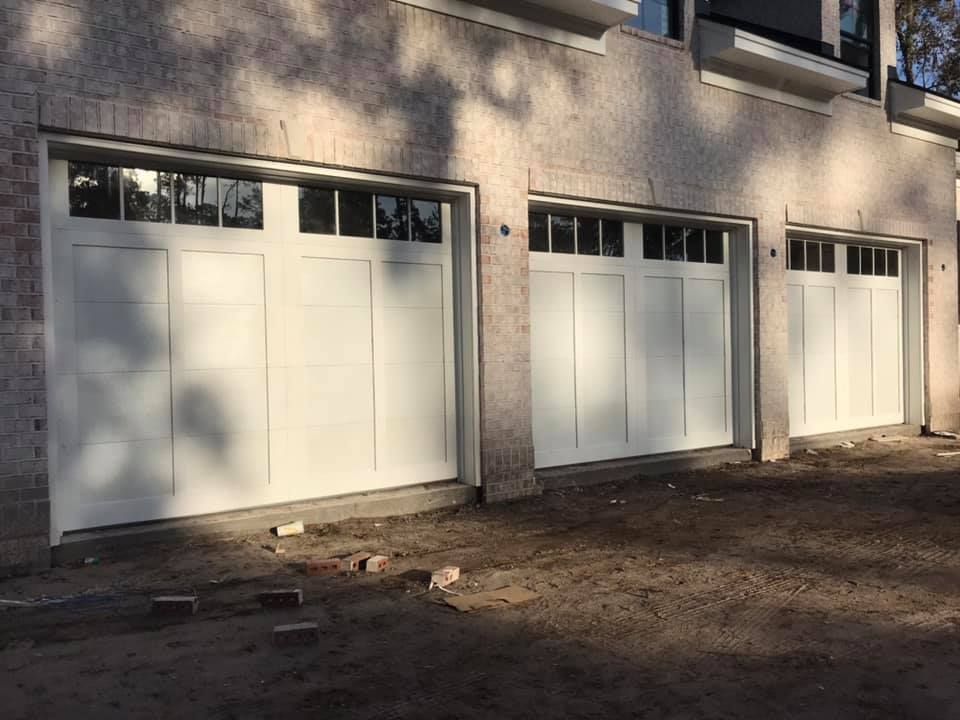 A row of white garage doors are sitting next to each other on the side of a building.