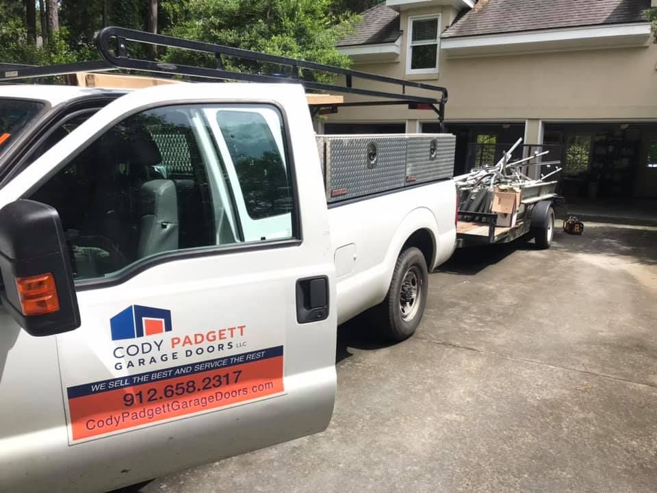 A white truck is parked in front of a garage door company.